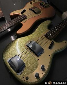 two guitars sitting on top of a table next to each other, one is green and the other is gold