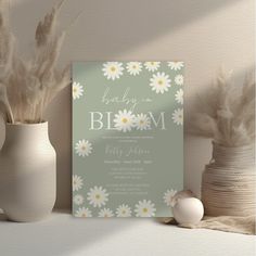 a baby is in bloom card next to two vases with feathers on them and an egg beside it