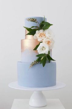 a three tiered blue cake with white flowers on top