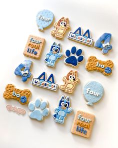 cookies decorated with cartoon characters are arranged on a white surface, including one dog and four cats