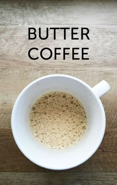 a white cup filled with coffee sitting on top of a wooden table