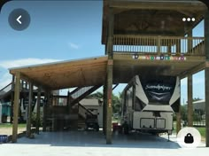 a camper parked under a wooden structure with stairs to the top and second story