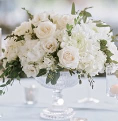 a vase filled with white flowers sitting on top of a table next to two candles