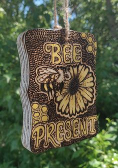 a bee present hanging from a rope in front of some trees and bushes with the words bees present on it