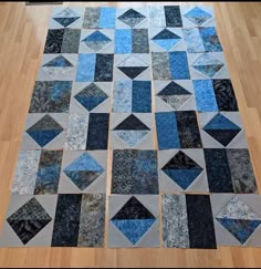 a blue and gray patchwork quilt on a wooden floor