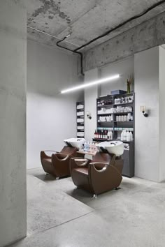 two brown chairs sitting next to each other on top of a cement floor in a room