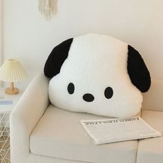 a white chair with a black and white dog pillow on it's back next to a lamp