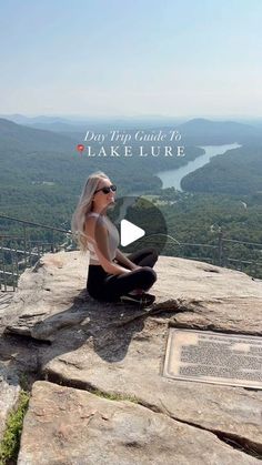 a woman sitting on top of a large rock next to a plaque with the words lake lure