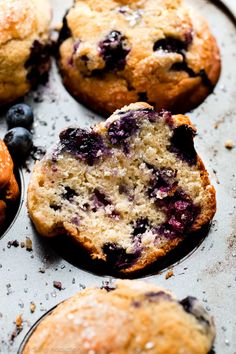 muffins with blueberries are sitting on a baking tray, ready to be eaten