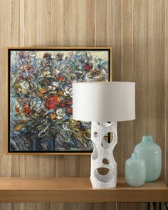 a table with a lamp, vase and painting on the wall