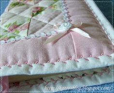 a pink and white quilted pillow sitting on top of a bed