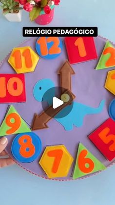 a child's hand holding a colorful clock with numbers on it