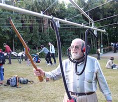 an older man with headphones on and holding a stick in his hand while standing next to other people