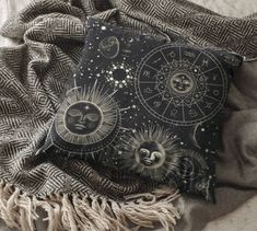 a black and white pillow with sun and moon designs on it next to a blanket