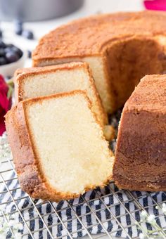 a cake that has been cut into pieces and is sitting on a cooling rack with berries in the background