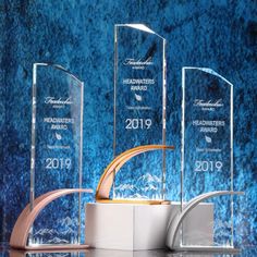 three clear glass awards on display in front of a blue background