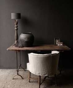 a table with two chairs and a vase sitting on it next to a lamp in a dark room