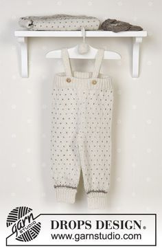 a white baby's outfit hanging on a wall next to a shelf with shoes