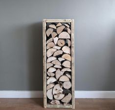 a stack of logs sitting on top of a hard wood floor next to a wall