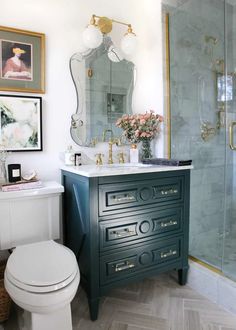 a white toilet sitting next to a green cabinet in a bathroom under a large mirror