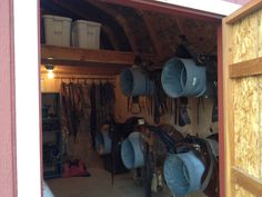 the inside of a horse barn with several saddles and hats hanging on the wall