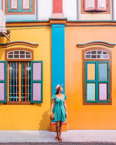 a woman standing in front of a colorful building