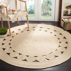 a large round rug in the middle of a living room with a chair and potted plant