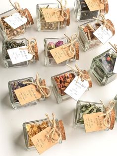 several small glass containers filled with different types of spices and tea bags tied in twine