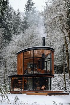 a round house in the middle of a snowy forest with trees and snow covered ground