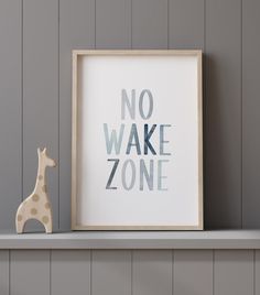 a wooden giraffe figurine sitting next to a framed print that says no wake zone