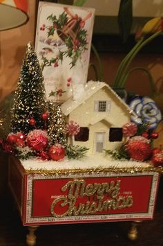 there is a christmas decoration on top of a small box with a house in it