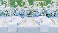 the table is set with blue and white flowers, silverware, and napkins