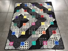 a black and white patchwork quilt on the floor in a room with tile floors