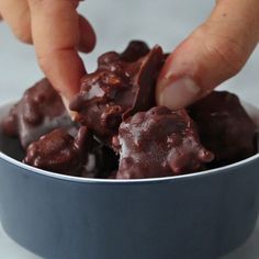 a person is picking up some kind of chocolate treat from a blue bowl on the table