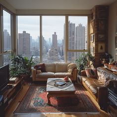 a living room filled with furniture and large windows overlooking the cityscape in the distance