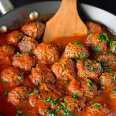 meatballs and sauce in a pan with a wooden spoon