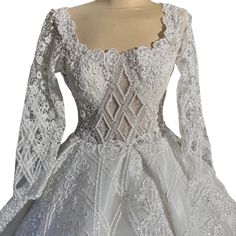 a white wedding dress with long sleeves and an intricate lace pattern on the bouncy skirt