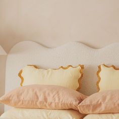 two pillows on top of a bed next to a lamp