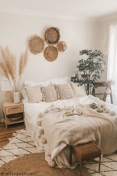 a bed with white sheets and pillows in a bedroom next to a plant on the wall