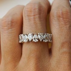 a woman's hand with a diamond ring on her left hand, showing the side stones