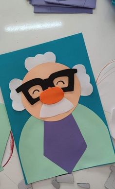 an old man with glasses on his face is cut out from construction paper and glue