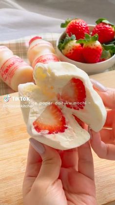 someone is peeling an egg shell with strawberries in the background