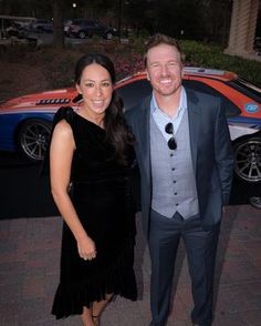 a man and woman standing next to each other in front of a sports car at an event