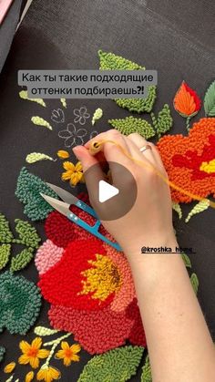 a woman is using scissors to crochet flowers on a piece of knitted fabric