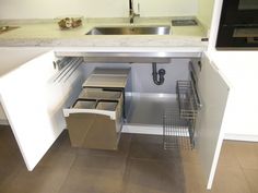 an open cabinet in the middle of a kitchen with sink and dishwasher on it