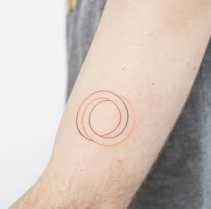 a man's arm with a tattoo on it that has an orange circle in the middle