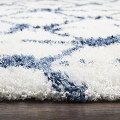 a blue and white area rug on the floor with wood flooring in the background