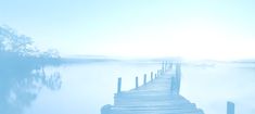 a dock in the middle of a body of water on a foggy day,