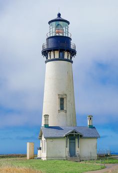 a white and blue light house sitting on top of a lush green field