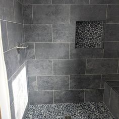 a walk in shower sitting next to a white toilet under a tiled wall and floor